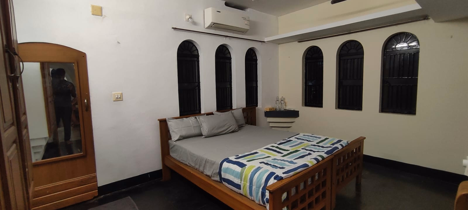 Wide bedroom view with bed, wardrobe, and arched windows
